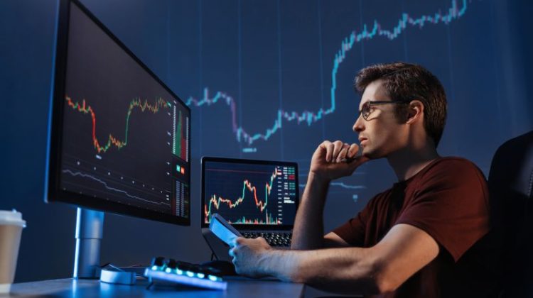 Crypto trader sitting in front of computers, making professional analysis of candlestick chart