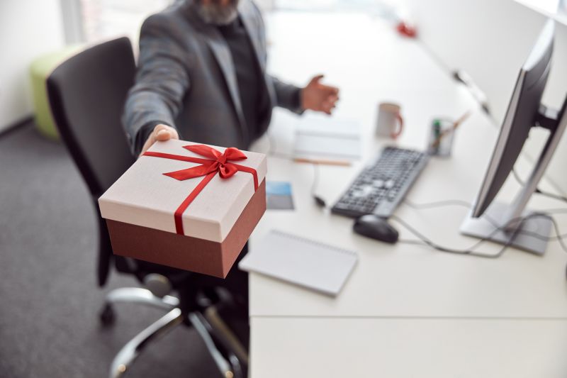 Happy office worker is holding a present and smiling