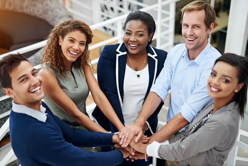 Portrait of a group of coworkers standing with their hands together in a huddle in an office