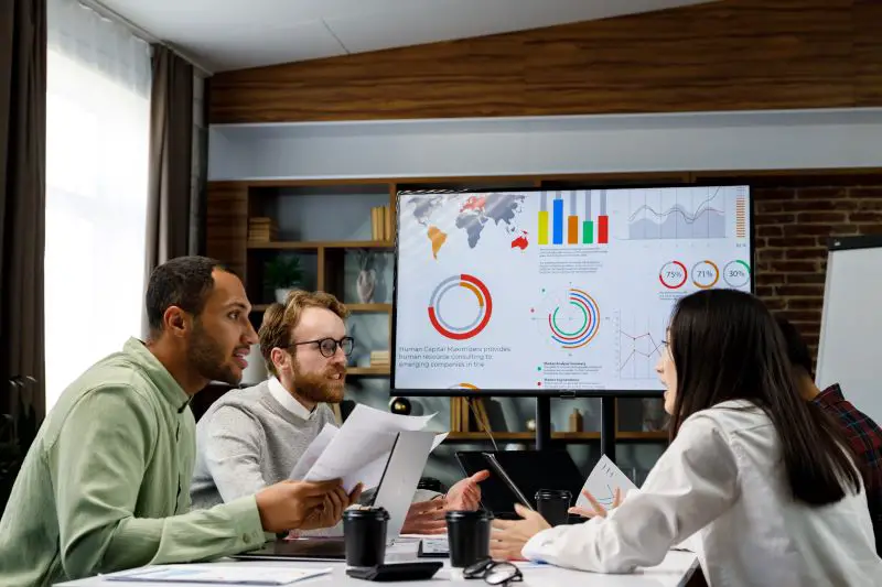 A team of young, mixed-race businesspeople is assessing the business metrics for the business retention strategy and audit.