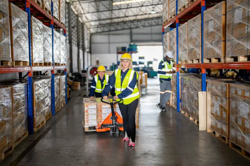 Worker Pulling Cardboard Boxes At Warehouse