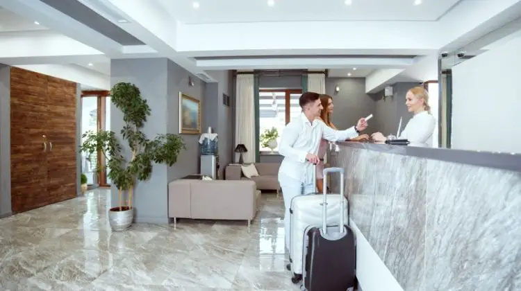 Visitors check in at a modern hotel reception with luggage during the day