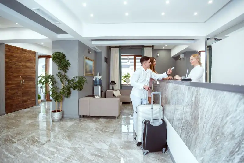Visitors check in at a modern hotel reception with luggage during the day