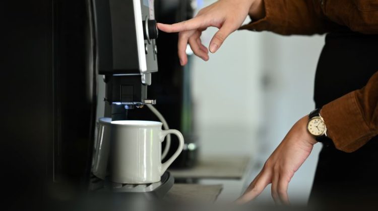 Closeup business woman using coffee machine in the office.