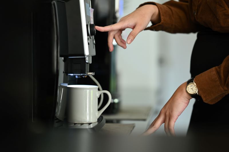 Closeup business woman using coffee machine in the office.