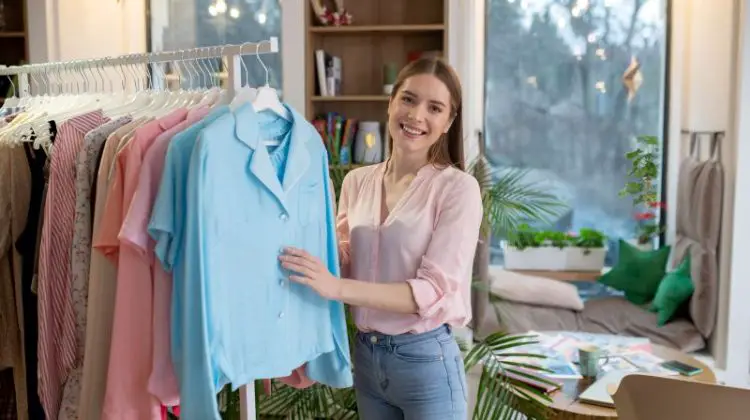 Young woman consultant showing women clothes presented in her showroom.