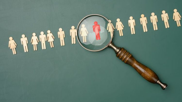 Wooden men and a magnifying glass on a green background. Recruitment concept, search for talented and capable employees, career growth