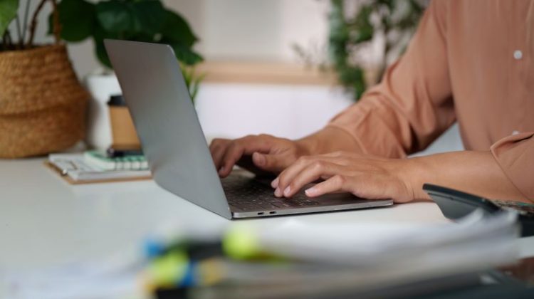 Close-up of hands typing a guest post on a laptop in a serene workspace.