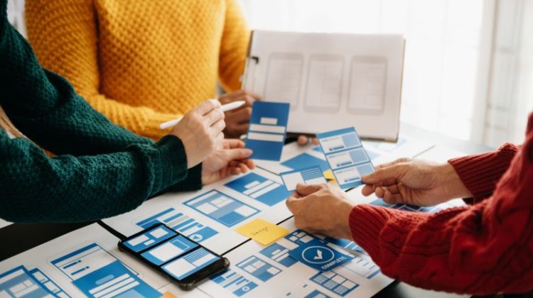 view of UI developer team brainstorming on their project with laptop, smartphone and digital tablet.