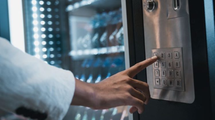 Close up hand of woman pushing button on vending machine for choosing a snack or drink.