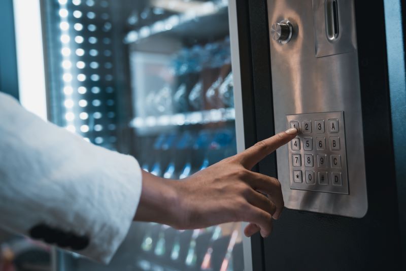 Close up hand of woman pushing button on vending machine for choosing a snack or drink.