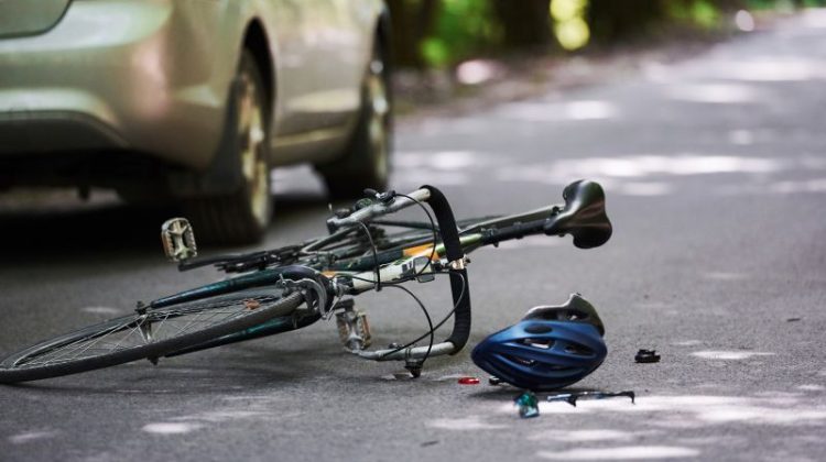 Bicycle and silver colored car accident on the road at forest at daytime