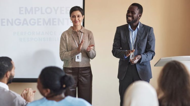 Successful mature coach and her assistant clapping hands in front of audience
