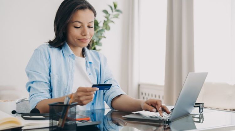 Attractive european lady entering code of credit card on laptop. Shopping from home, money transfer, recurring payment