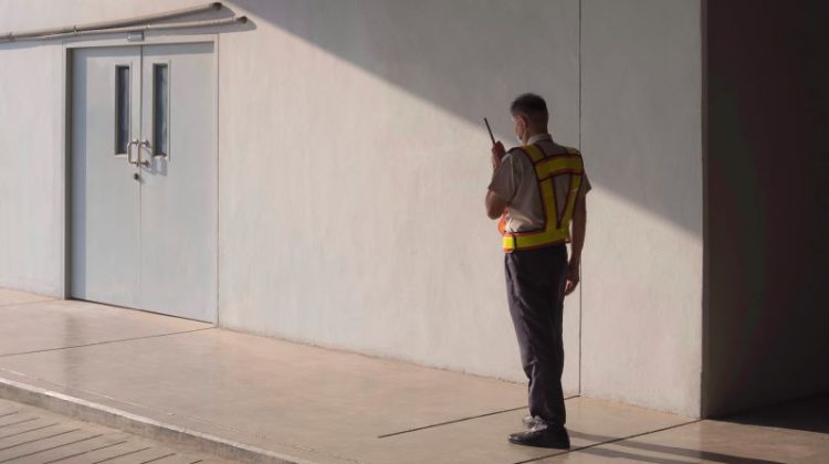Lone security guard using walkie talkie while working in parking garage