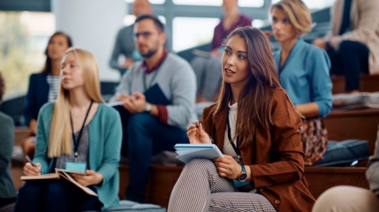 Young businesswoman writing notes while participating in an MBA lecture at a University.
