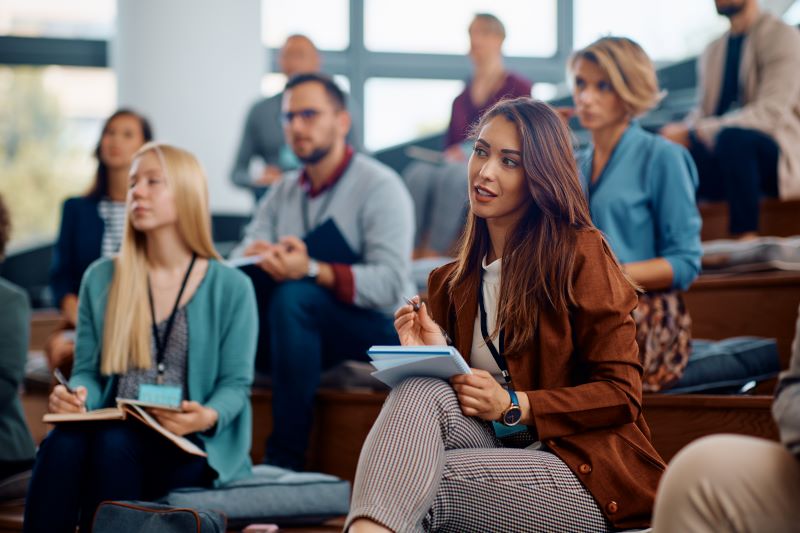 Young businesswoman writing notes while participating in an MBA lecture at a University.