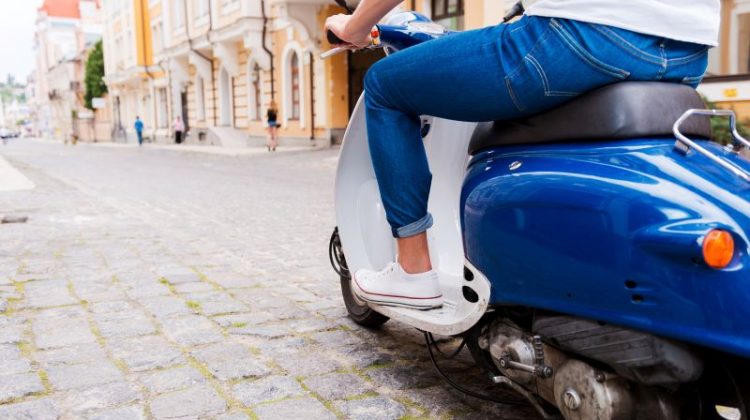 Rear view cropped image of a young man riding a scooter along the street
