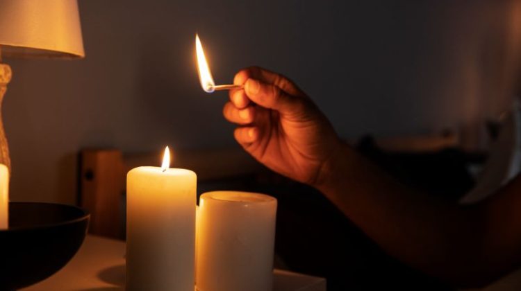 Side view hand lighting candle during a blackout