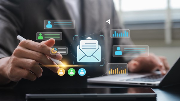 Businessman using a stylus and laptop to manage an automated email marketing campaign with digital analytics overlays.