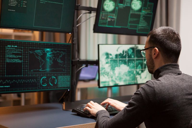 Man Coding on Multiple Monitors at Workplace