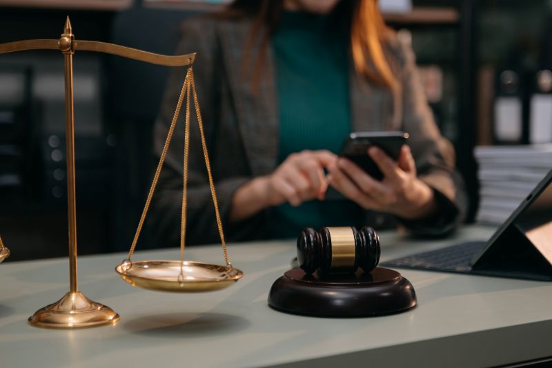 Woman Lawyer Using Mobile Phone with Gavel and Scales