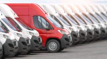 Red delivery van in a row of white vans. Best express delivery and shipemt service concept.