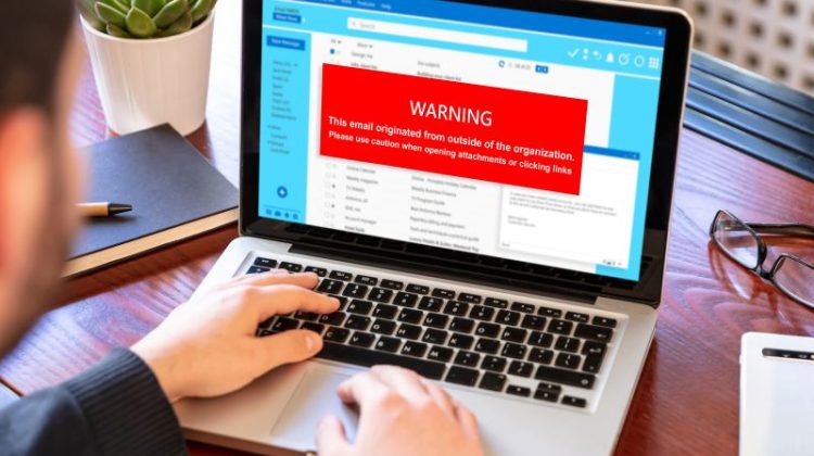 Email Scam Warning on Laptop with User Typing
