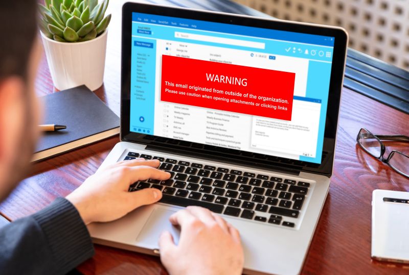 Email Scam Warning on Laptop with User Typing