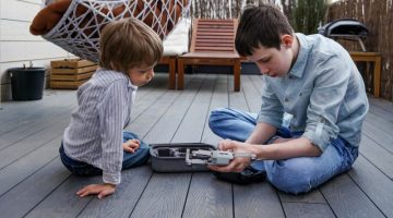 Modern technology. Two siblings boys unpacking and assembling new flying machine drone on terrace