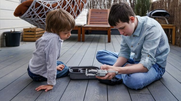 Modern technology. Two siblings boys unpacking and assembling new flying machine drone on terrace
