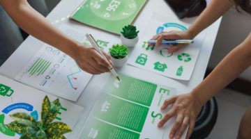 Two adults are reviewing the ESG principles at a table indoors with themes of environment, social, and governance printed on them.