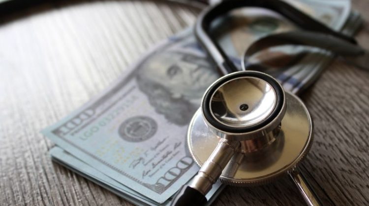 Medical Stethoscope Resting on Stack of Cash