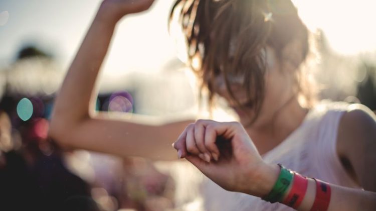 Festival attendee dancing while wearing colourful branded cloth wristbands