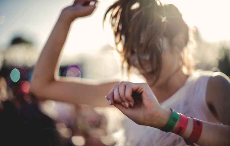 Festival attendee dancing while wearing colourful branded cloth wristbands