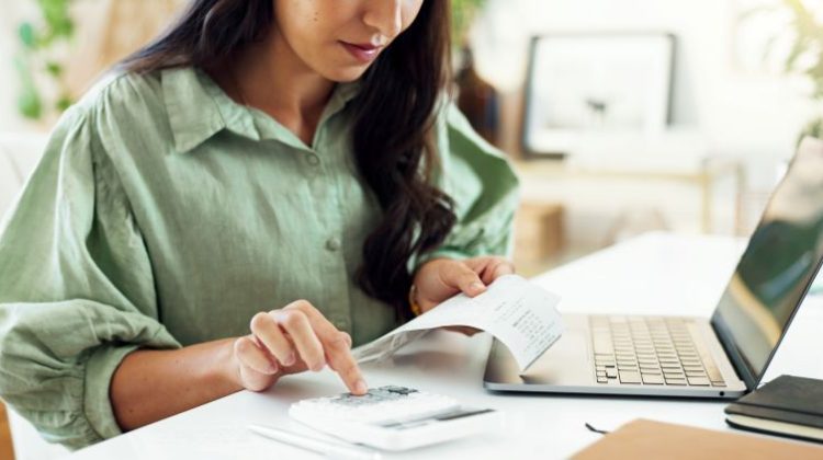Business owner reviewing an invoice and calculating payments on a laptop.