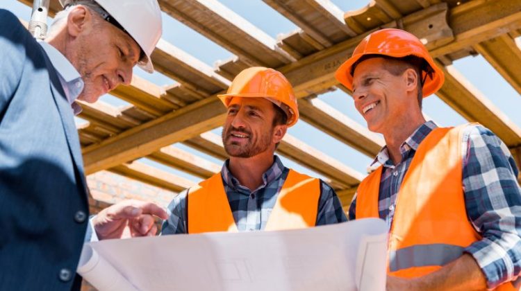 Construction manager and contractors reviewing building plans on an active jobsite.
