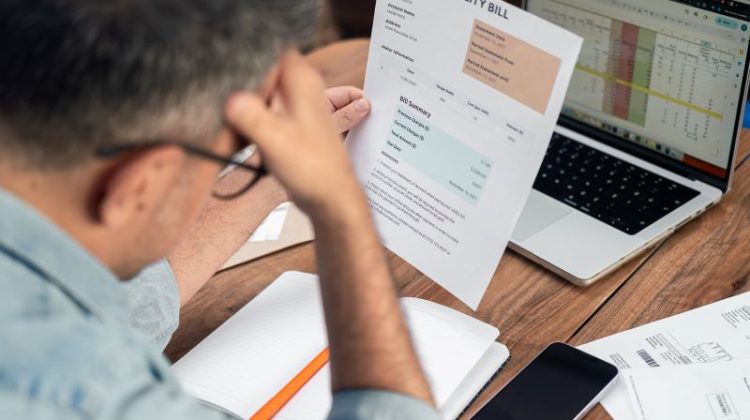 Small business owner reviewing bills and financial documents while facing financial pressure.