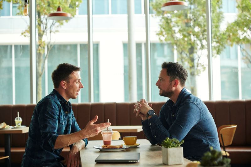 Two small business owners having a networking conversation over coffee in a café