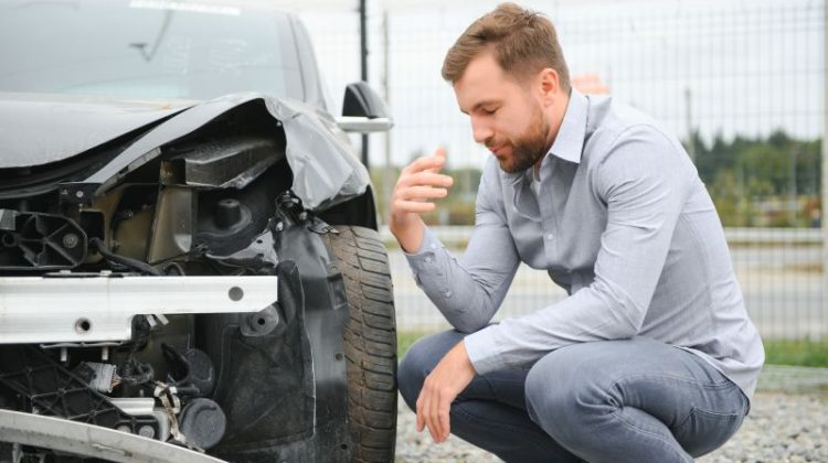 Self-employed professional assessing a damaged car after an accident that could disrupt work and business income.
