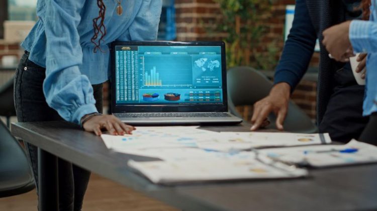 Business professionals analyzing financial market data and exchange rate trends on a laptop.