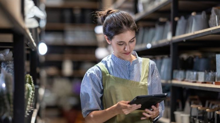 Retail employee using a tablet to manage stock and daily shop floor tasks.