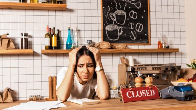 Stressed small business owner reviewing financial paperwork in a closed café