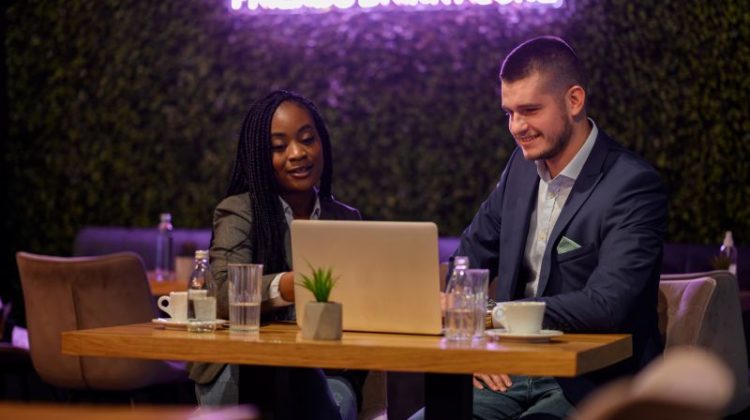 Two business professionals discussing opportunities on a laptop, representing the benefits of buying franchises in Birmingham.